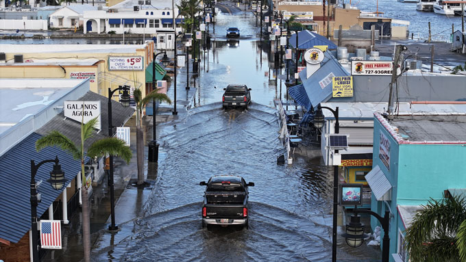 A pile of debris in water is pushed up against the side of a bridge.